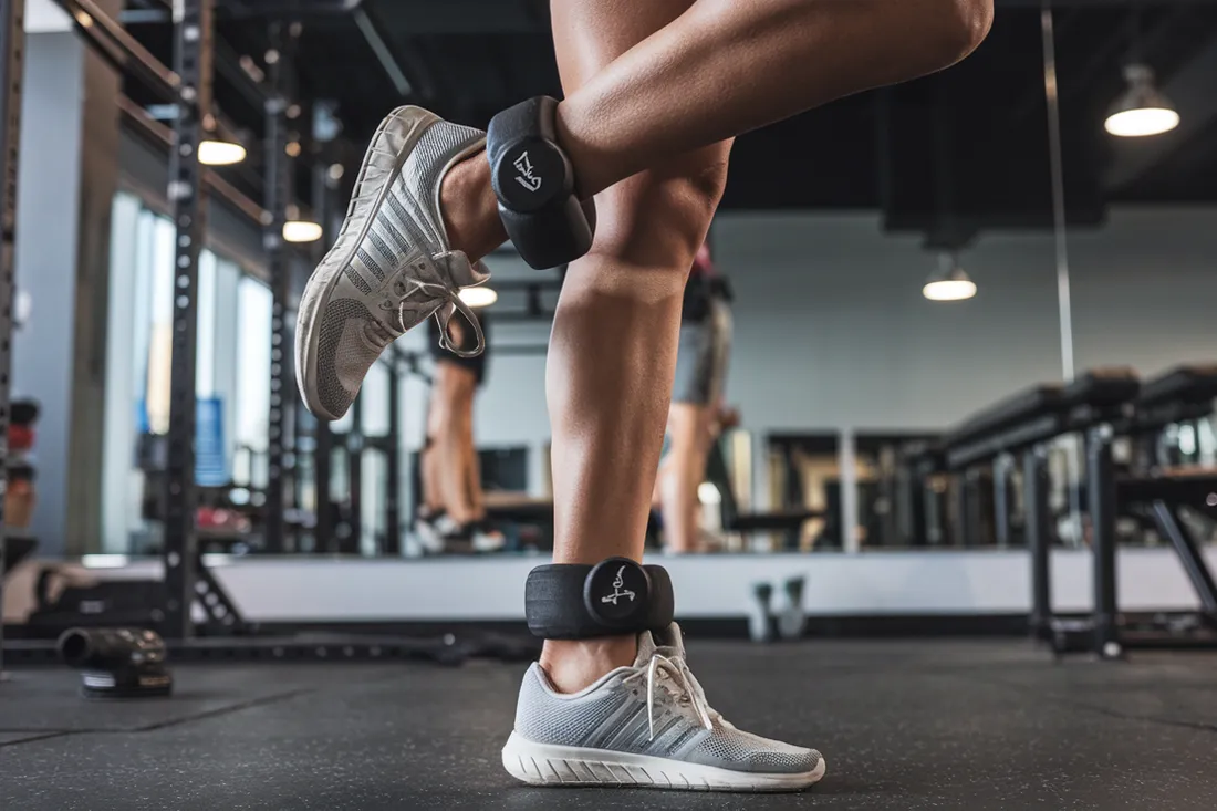 A close-up shot of a person's legs performing a leg raise exercise with ankle weights strapped securely around their ankles