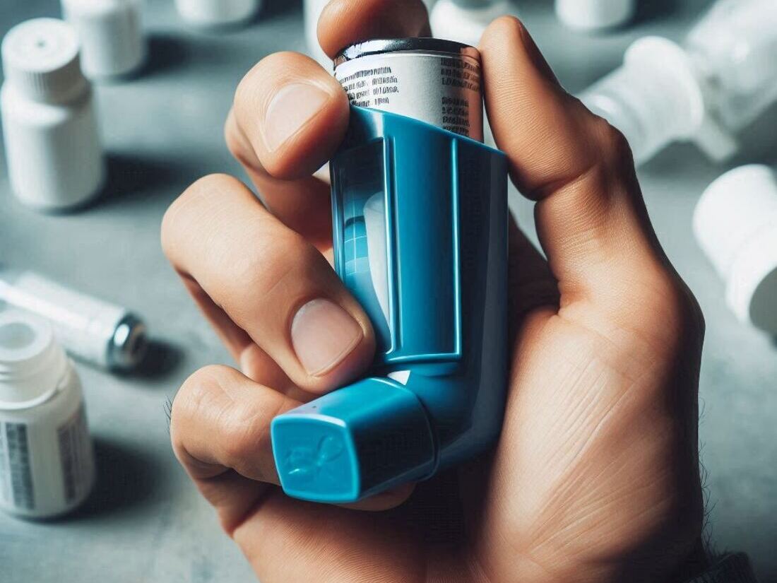 A hand holding a blue inhaler