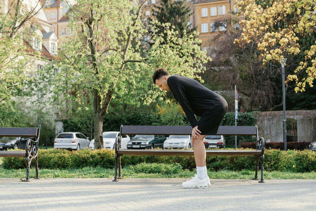 A person attempting a forward fold with difficulty reaching their toes, showcasing a sign of tight hip flexors