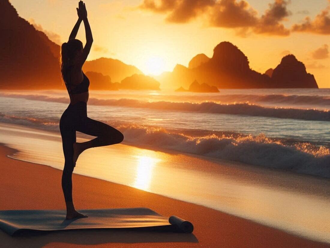 A person doing yoga poses on a beach mat at sunset