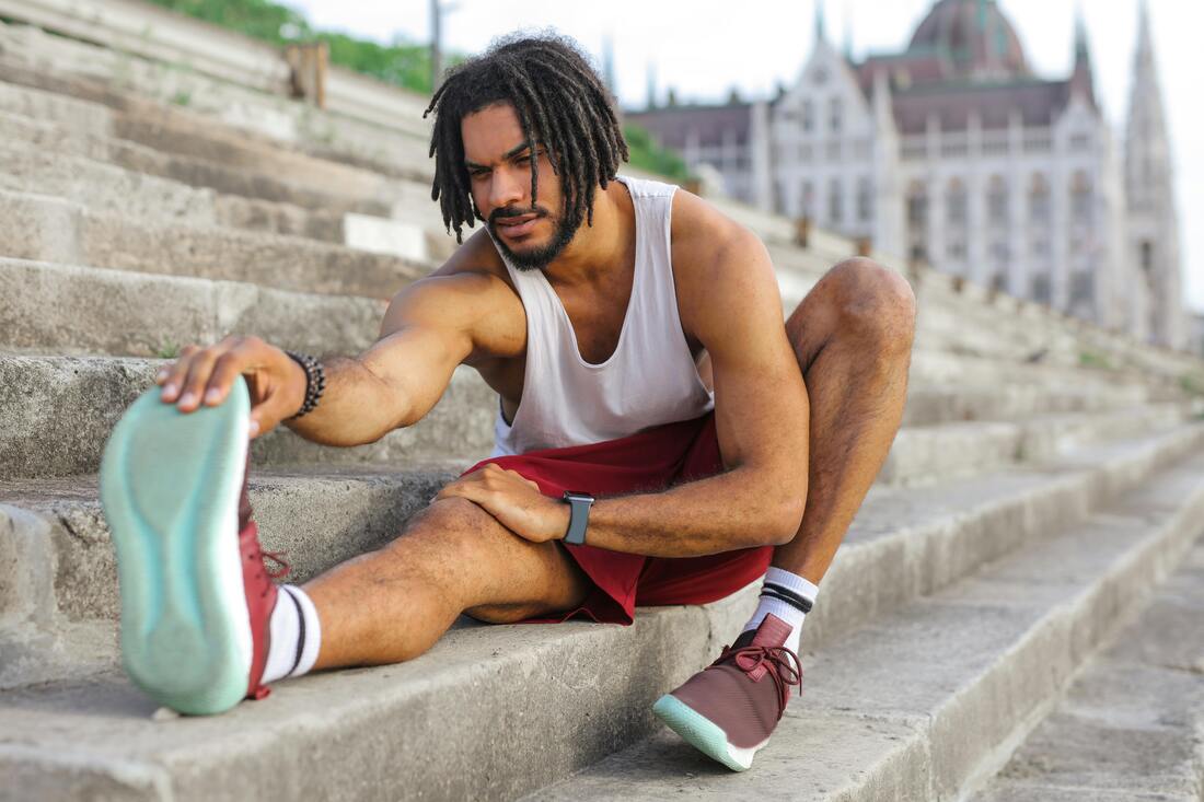 A person sitting and reaching to touch their toes, demonstrating good posture with a straight back and flat feet