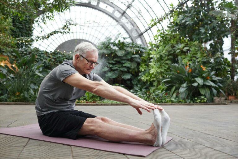 A person sitting on the floor, stretching to touch their toes