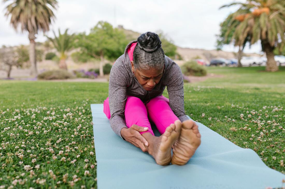 A person sitting on the mat frustrated while trying to touch their toes