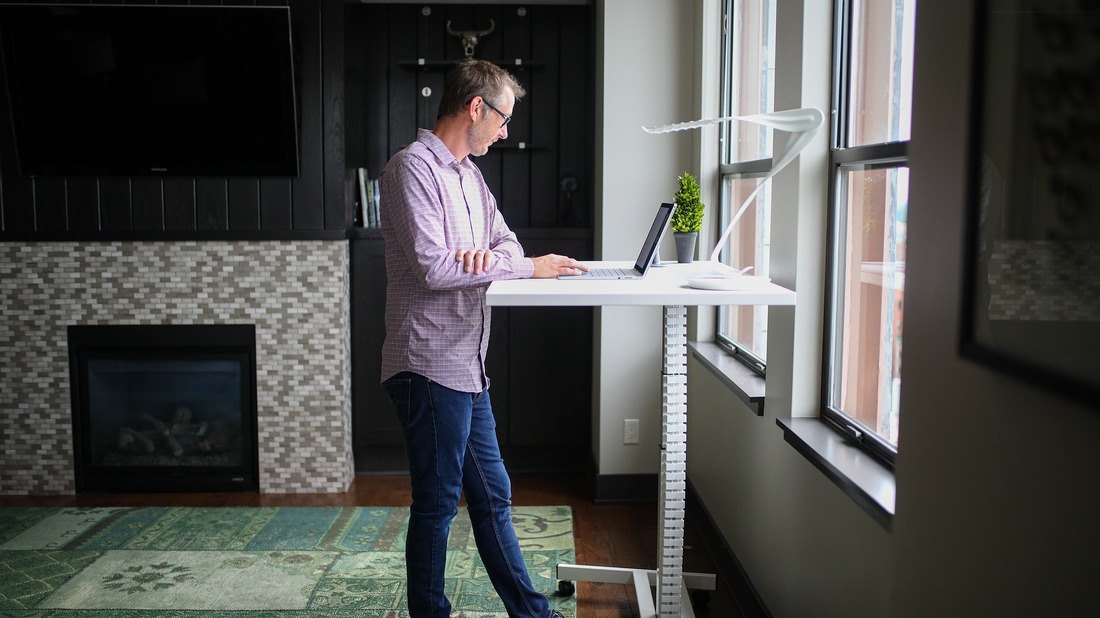 A person standing at a standing desk, working on a computer with good posture.