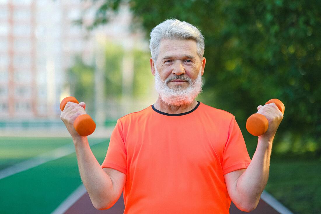 Cheerful aged person working out with dumbells