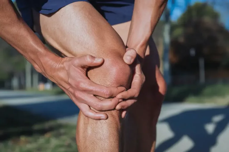 Close-up of a person holding their knee in pain during a run