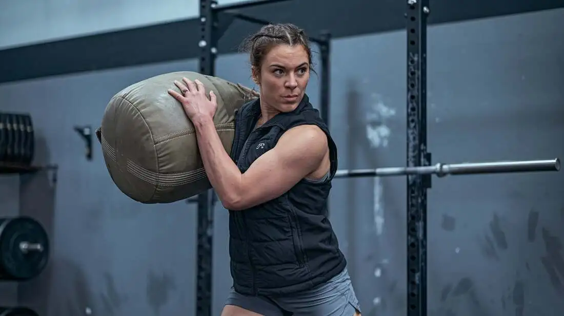 Woman performing a sandbag twist, engaging her core muscles for stability