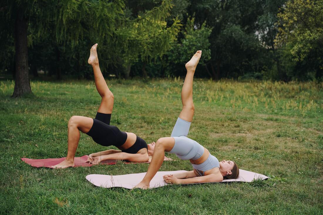 Persons performing a glute bridge with leg extension, lying on their back with hips lifted off the ground and one leg extended towards the ceiling