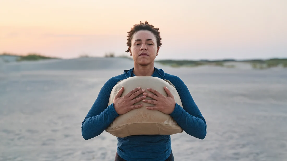 Person carrying a sandbag to their chest, and engaging their core muscles