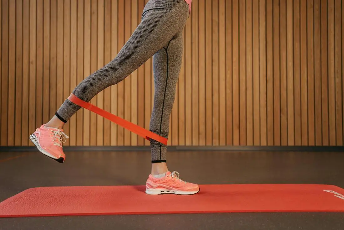 A woman performs standing kickbacks using a resistance band to target her glutes