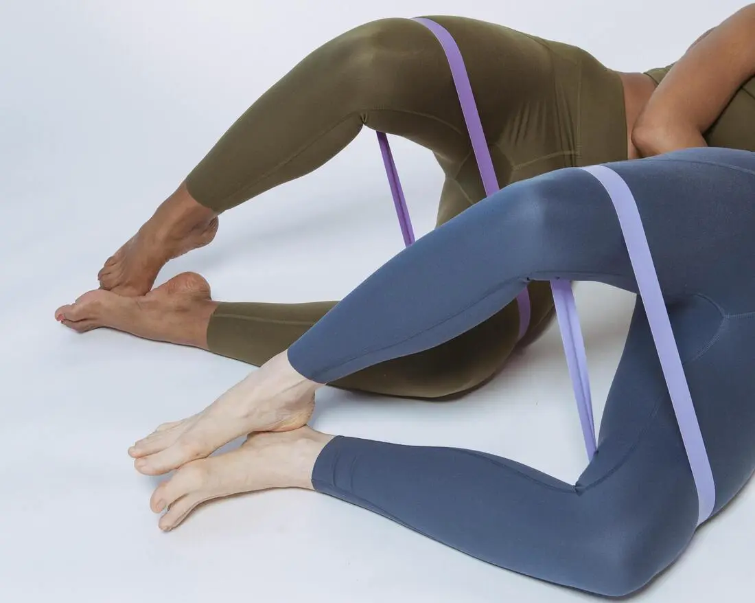 A woman engages her hip abductors by performing clamshells with a resistance band