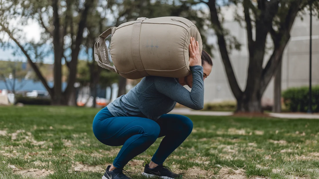 A person performing sandbag exercises outdoors, emphasizing the portability and versatility of sandbag training