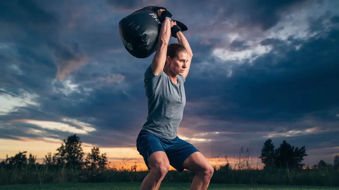 A person performing a full-body sandbag workout