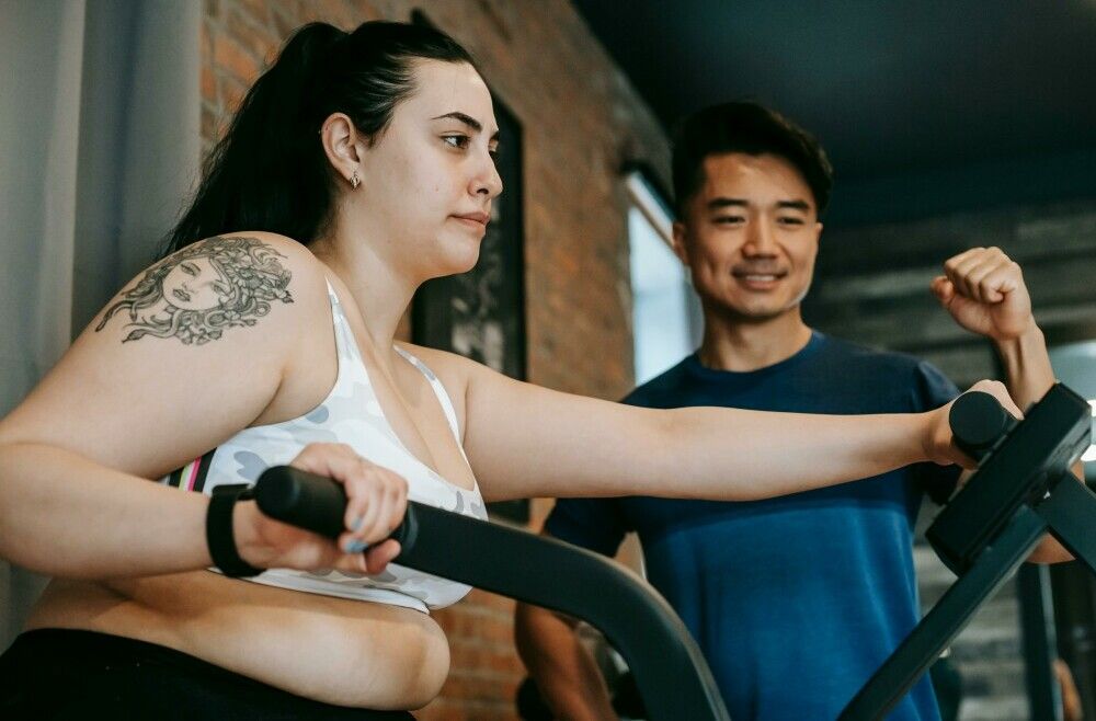 A Young Woman Training at the Gym with Trainer