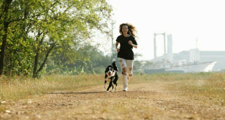 A Young Woman Running Outside With Her Dog